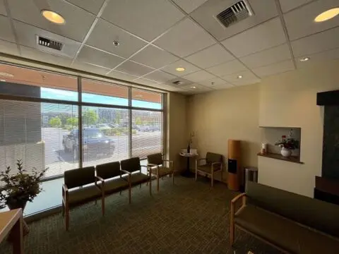Interior of a room with chairs, large windows letting in natural light, and a few decorations on the wall.