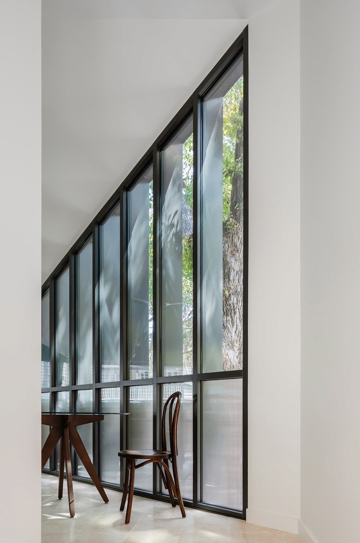Full-height glazed wall within the Treehouse, opening the interior to garden views and creating a strong visual connection between living space and landscape.