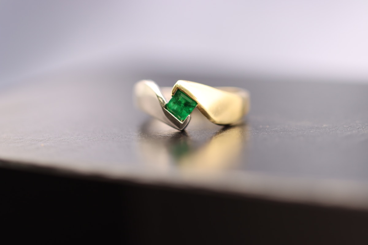 a gold ring with a green stone sitting on a table