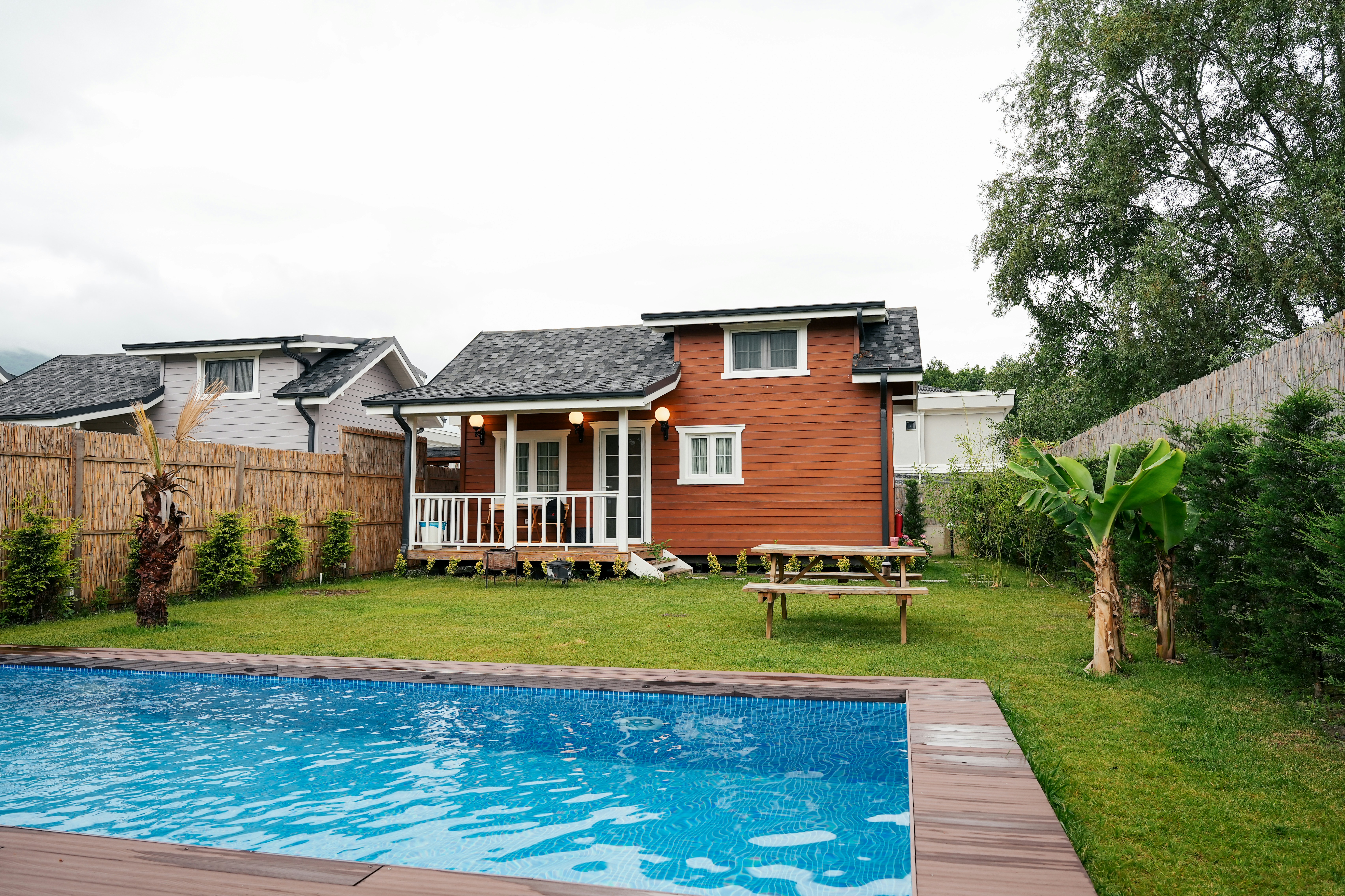 An expansive estate surrounded by lush trees, featuring a large, elegant mansion with a blue roof.