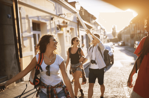 Group of friends walking and laughing down a sunny street.