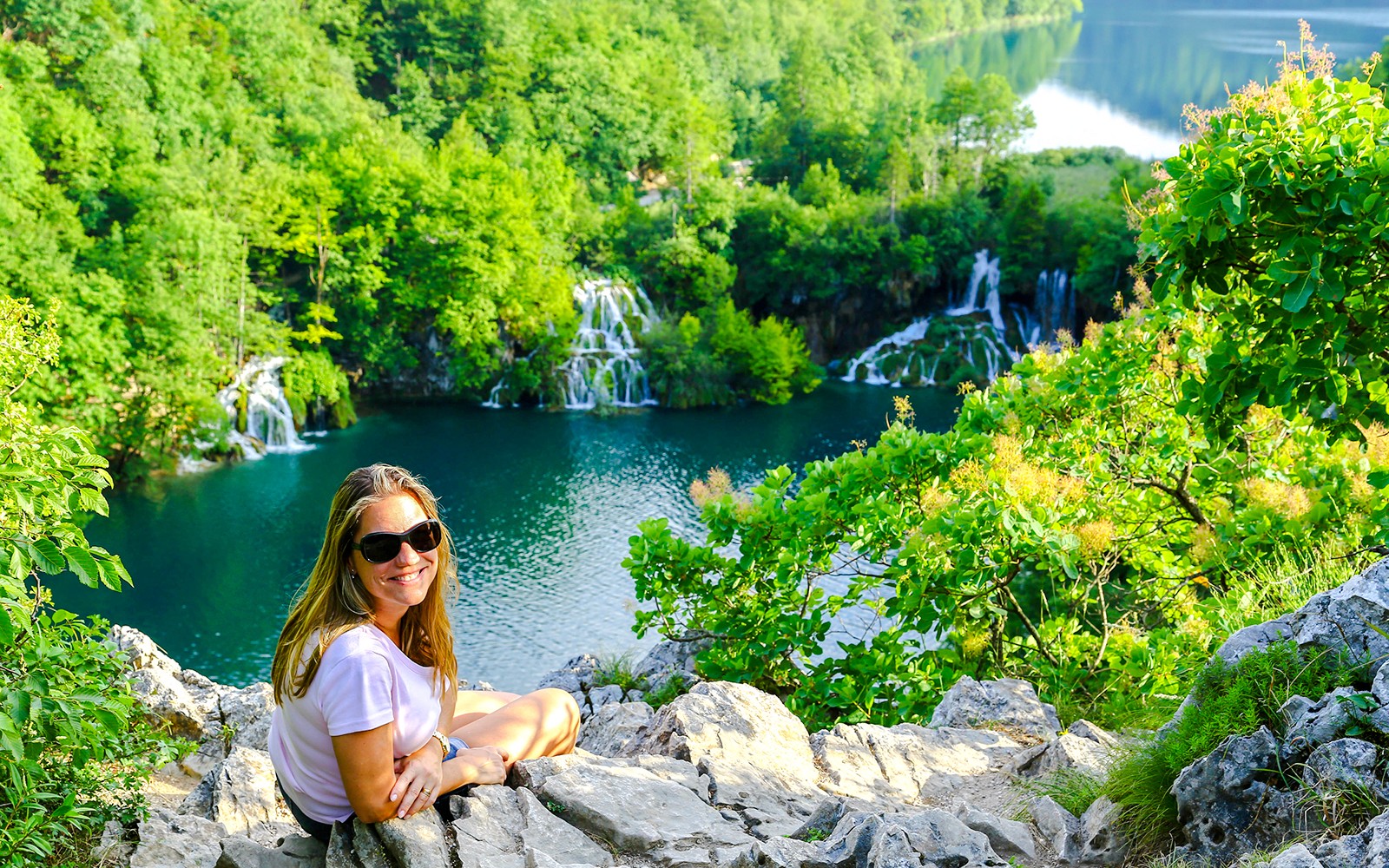 遊客坐在石頭上，俯瞰克羅地亞普利特維采湖的瀑布。