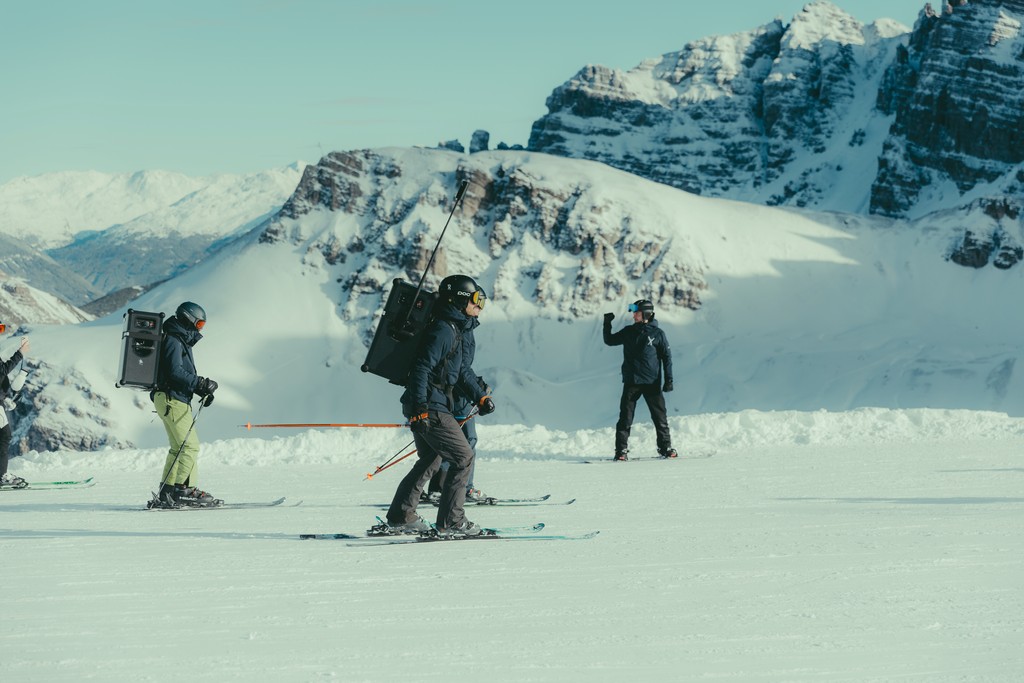 Skier racing down snowy slope in winter gear and red boots.