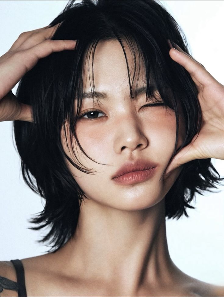 Close-up portrait of a blonde woman in translucent pink glasses and a white shirt on a soft blue background.
