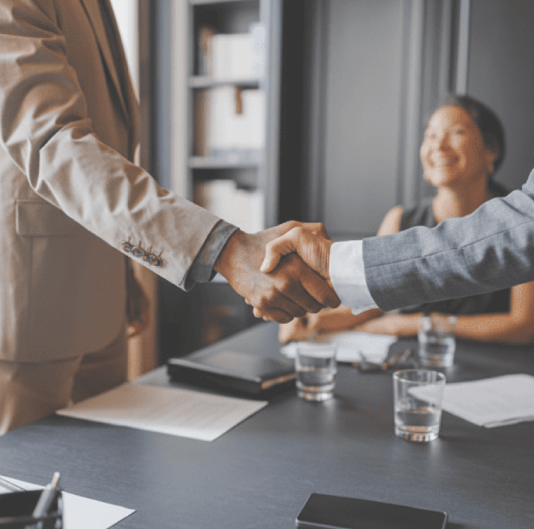 Handshake in foreground with woman in background