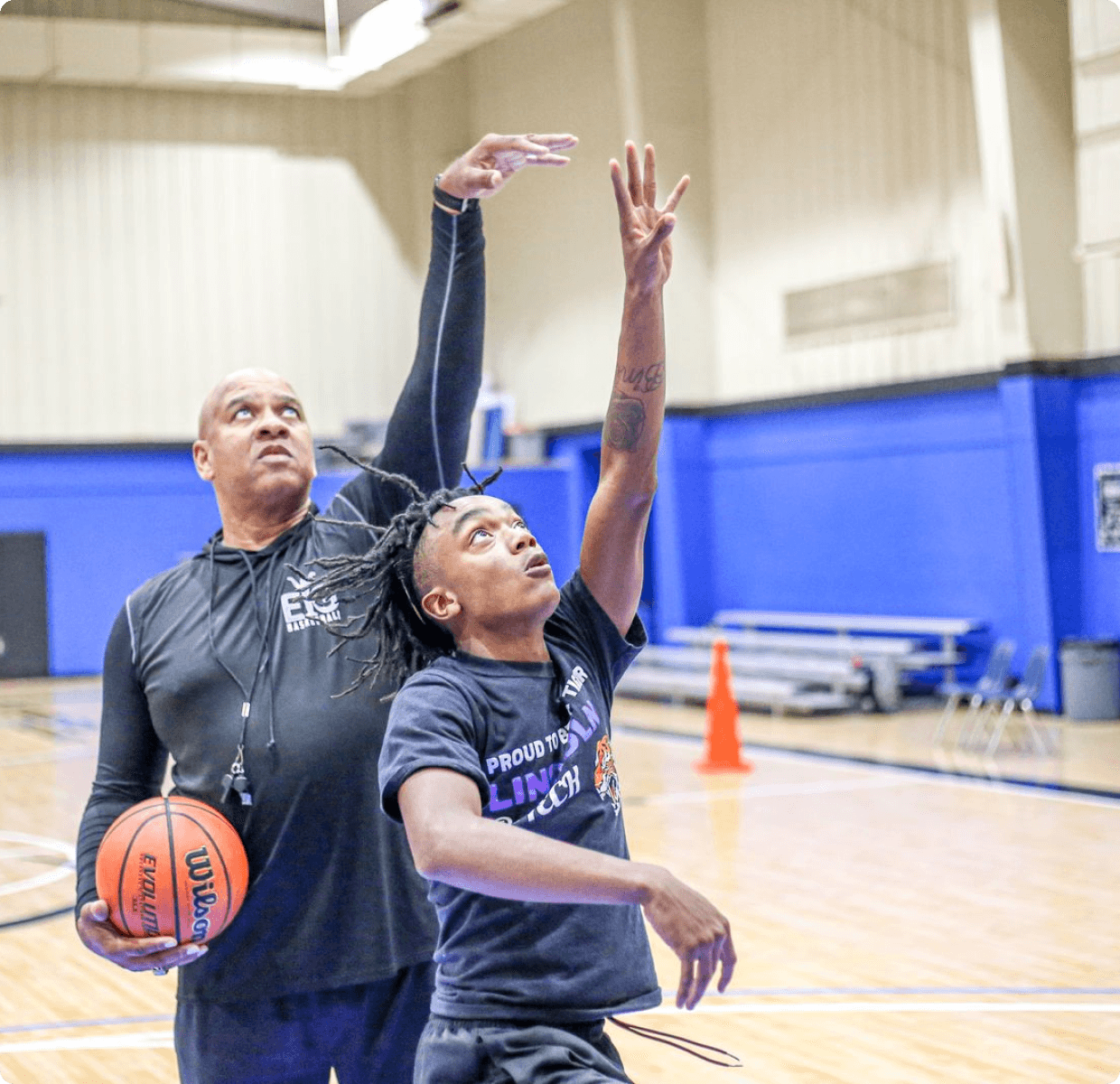 Coach training a young athlete on basketball shooting technique at Elevate Your Game program.