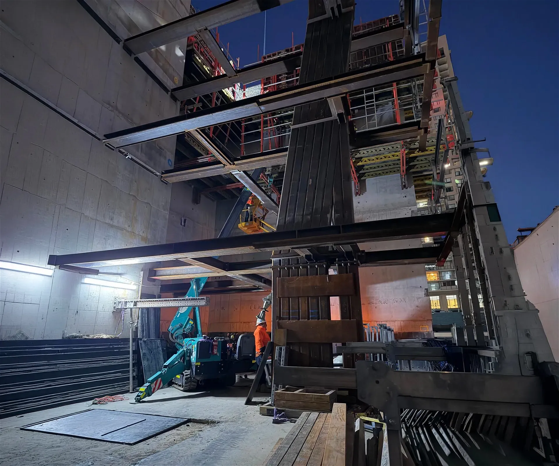 Construction site with steel beams and concrete walls.