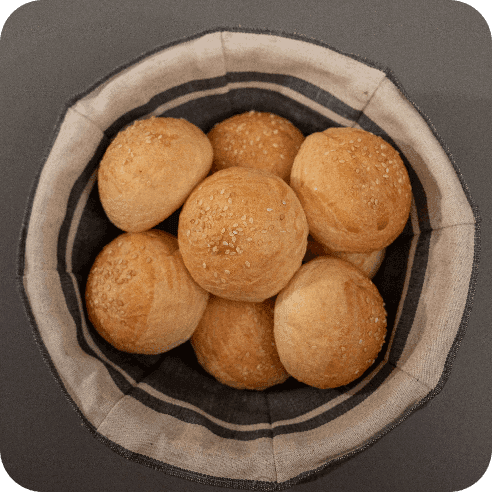 Cesta artesanal con panecillos de brioche de masa madre recién horneados, listos para compartir.
