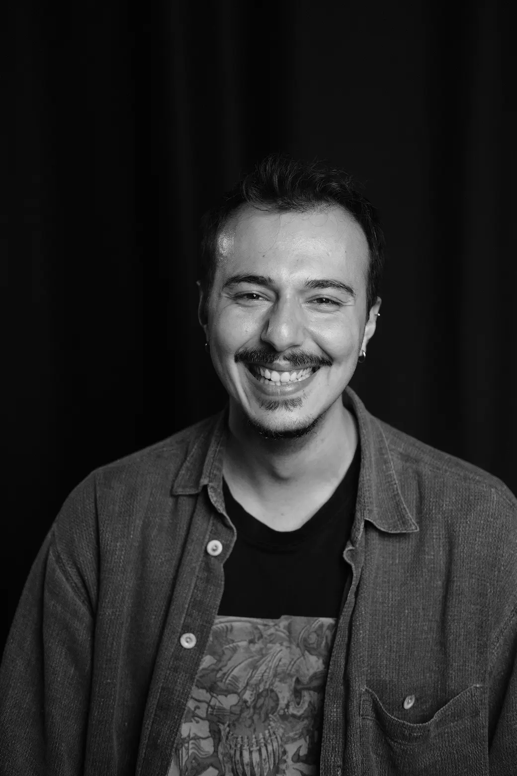 Black-and-white portrait of a laughing Meridian Studio team member in a corduroy shirt