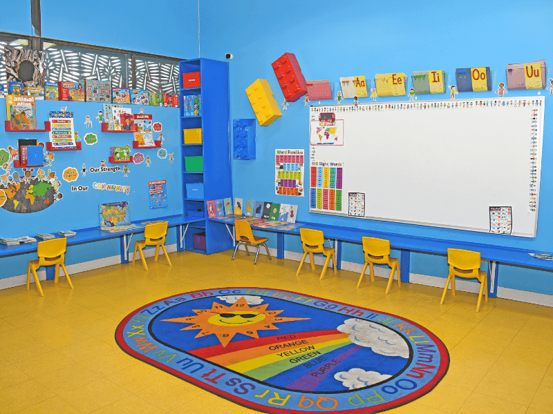 Bright preschool classroom with a circle time rug, child-sized seating, and engaging learning stations at Little Adventures Academy.
