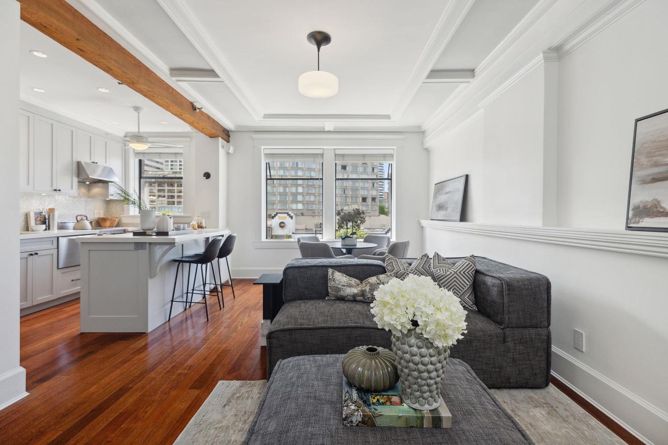 Bright, modern living room with gray sofas, a coffee table, and elegant décor against a white backdrop.
