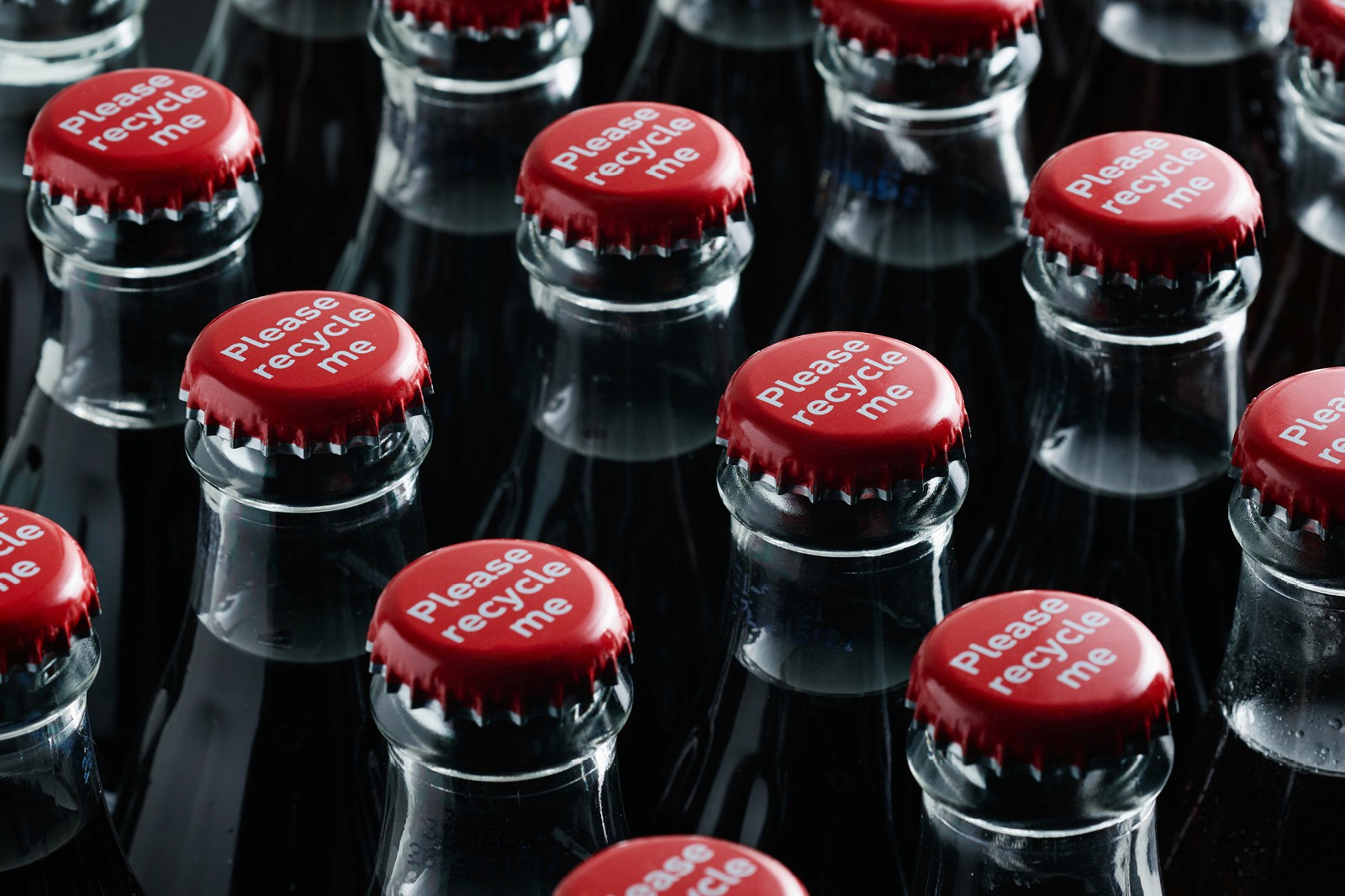 Multiple glass bottles with red caps and "Please recycle me" text, promoting recycling and sustainability with eco-friendly packaging.