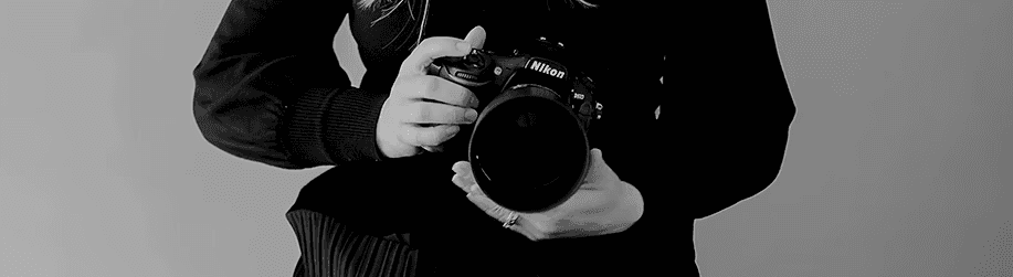 Abstract macro of a glass drop forming a black-and-white flower shape through light refraction on a soft gray background.