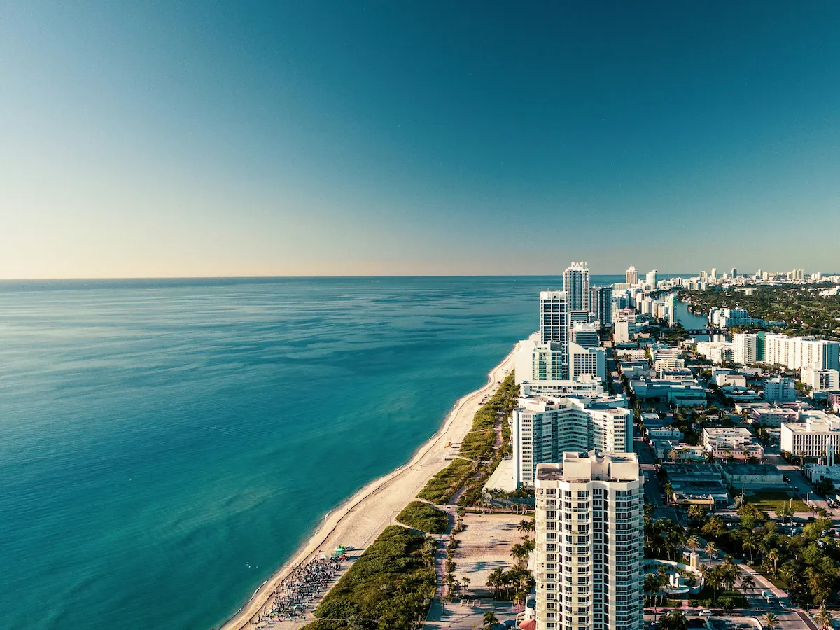 Aerial view of Miami Beach coastline with turquoise Atlantic Ocean and high-rise hotels along the shore.