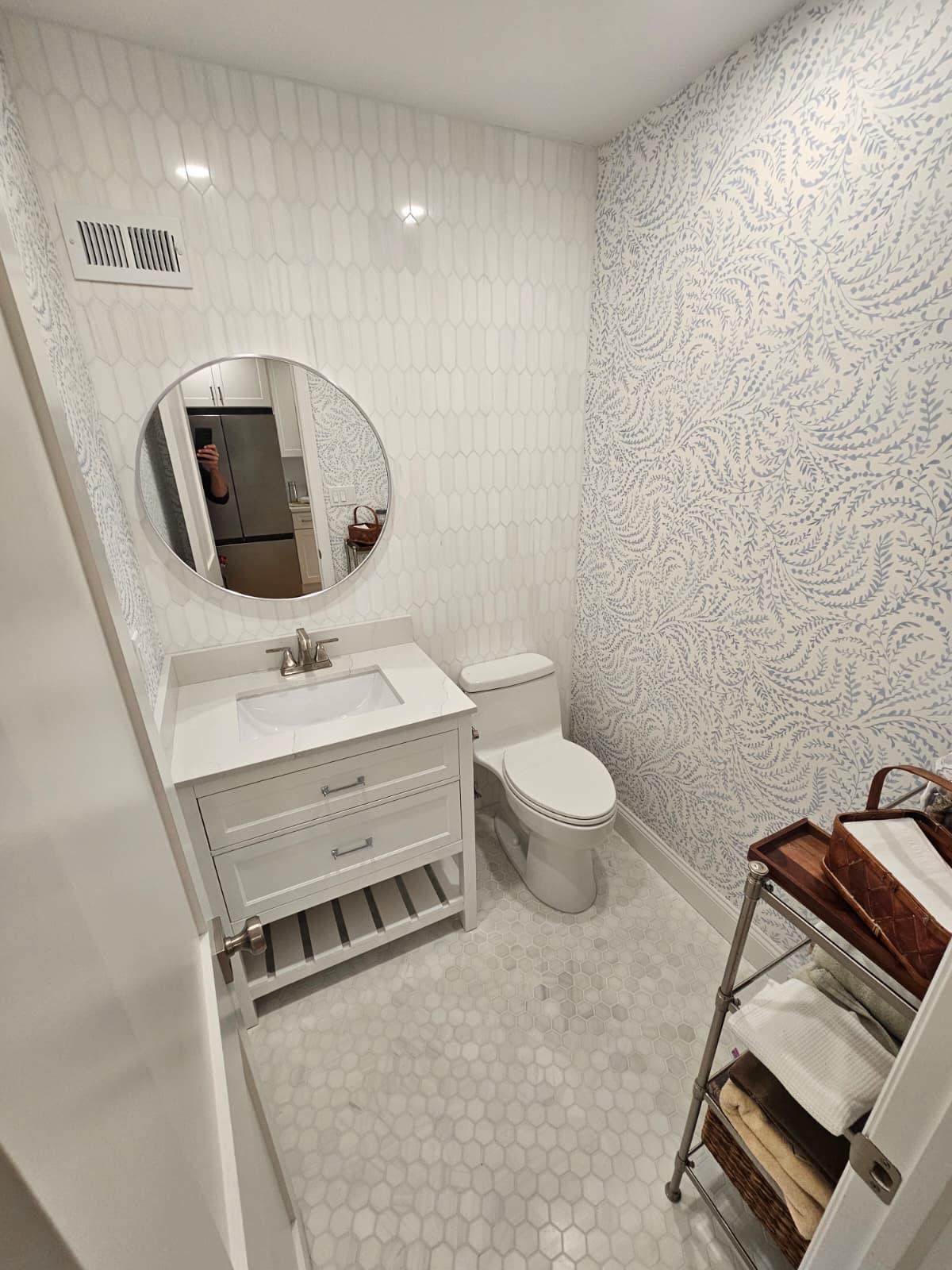 Powder room renovation with custom vanity, patterned wallpaper, and round mirror