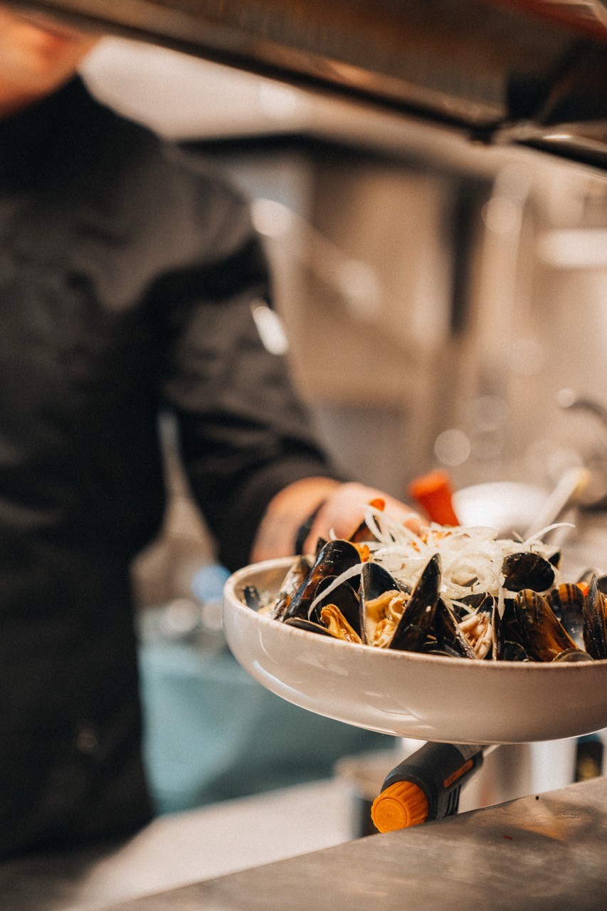 chef handing out a plate of dinner in restaurant kitchen