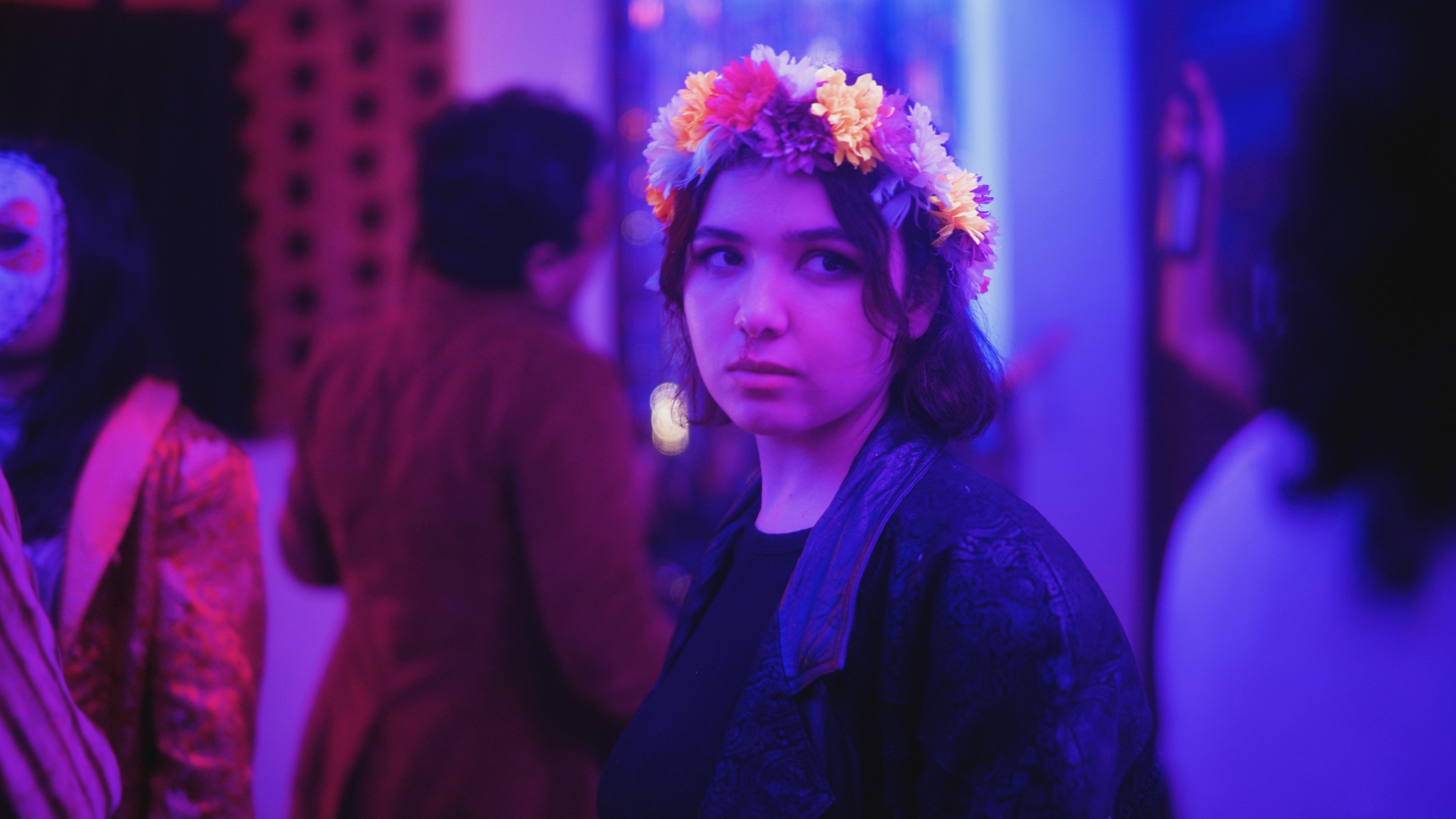 A close-up of a person wearing green-tinted glasses, with a serious expression and smooth skin.