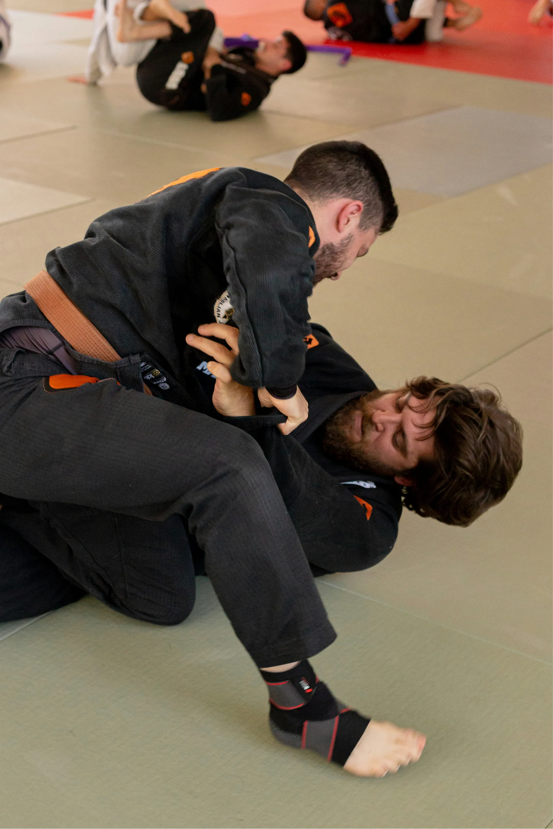 Two Brazilian Jiu-Jitsu students practicing ground techniques.