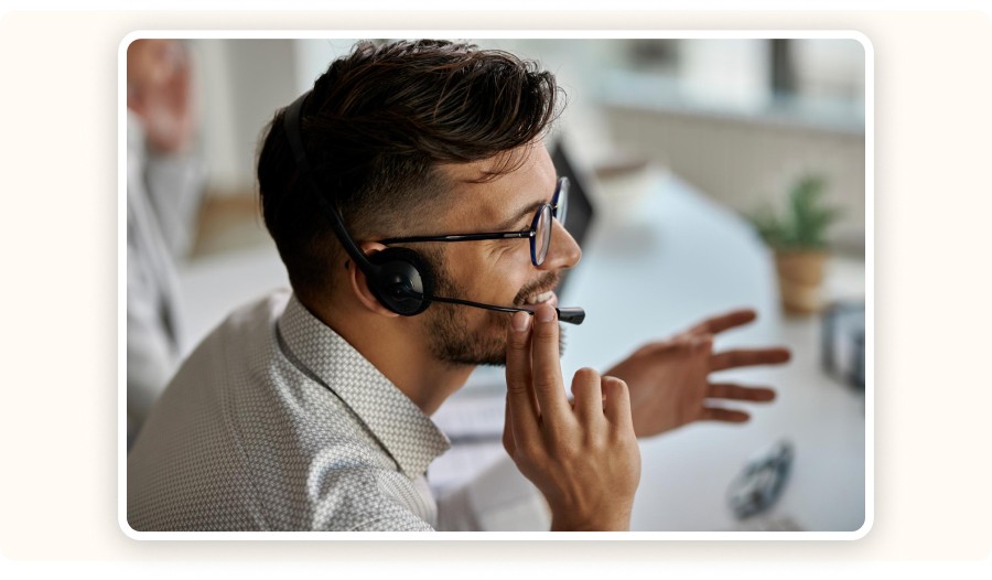 Customer support agent wearing headset assisting client at office desk
