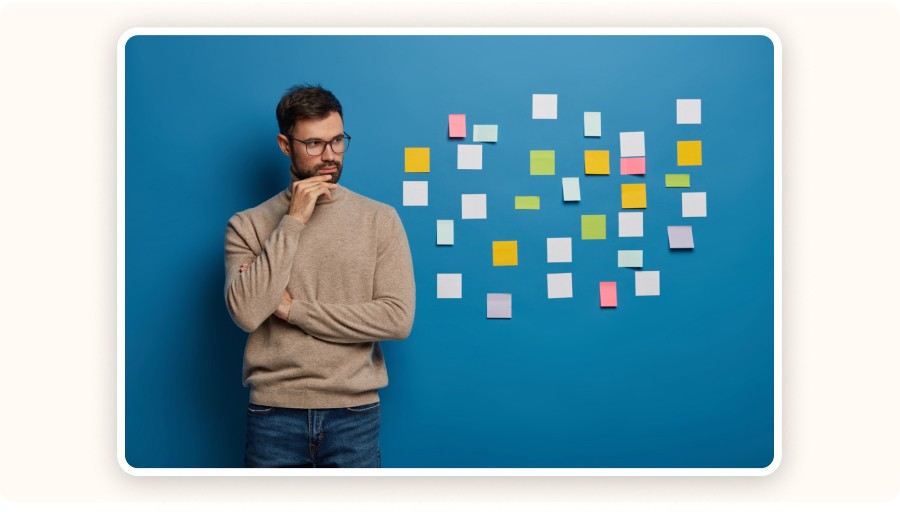 Man thinking while looking at colorful sticky notes on blue background