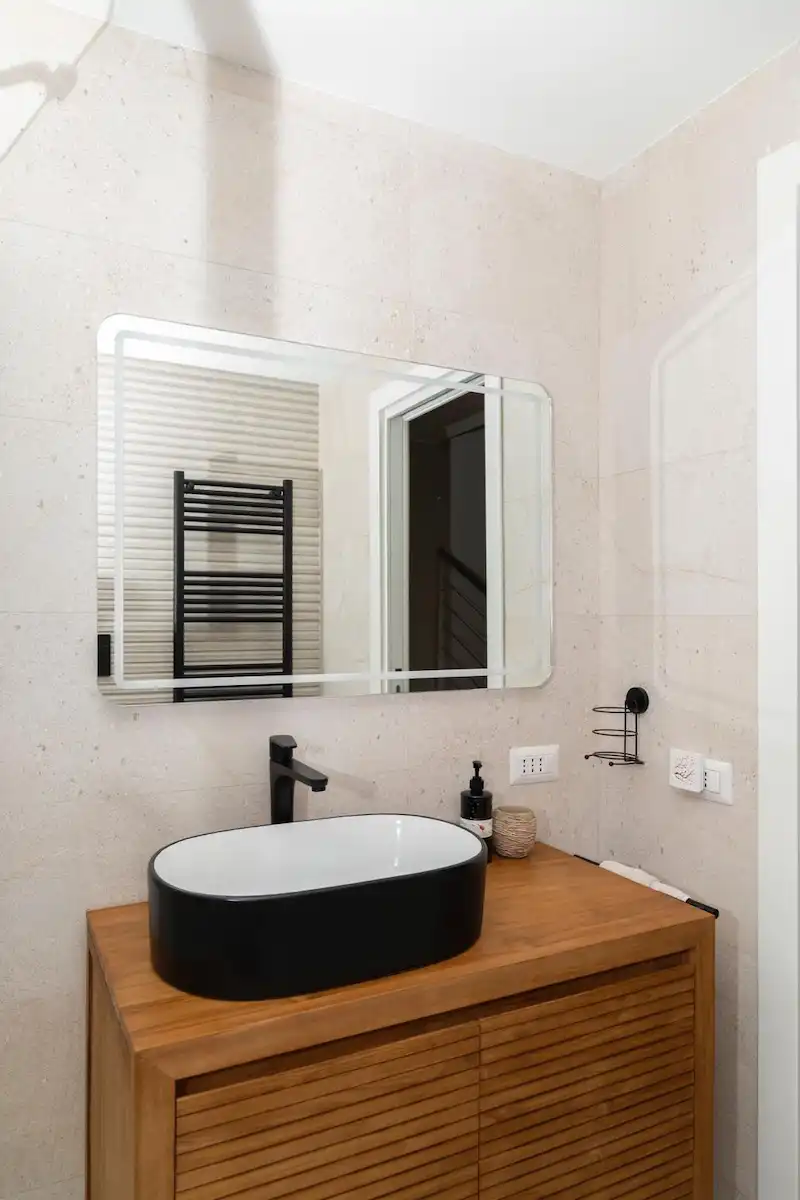 dettaglio di consolle bagno in legno elegante con lavabo nero e bianco