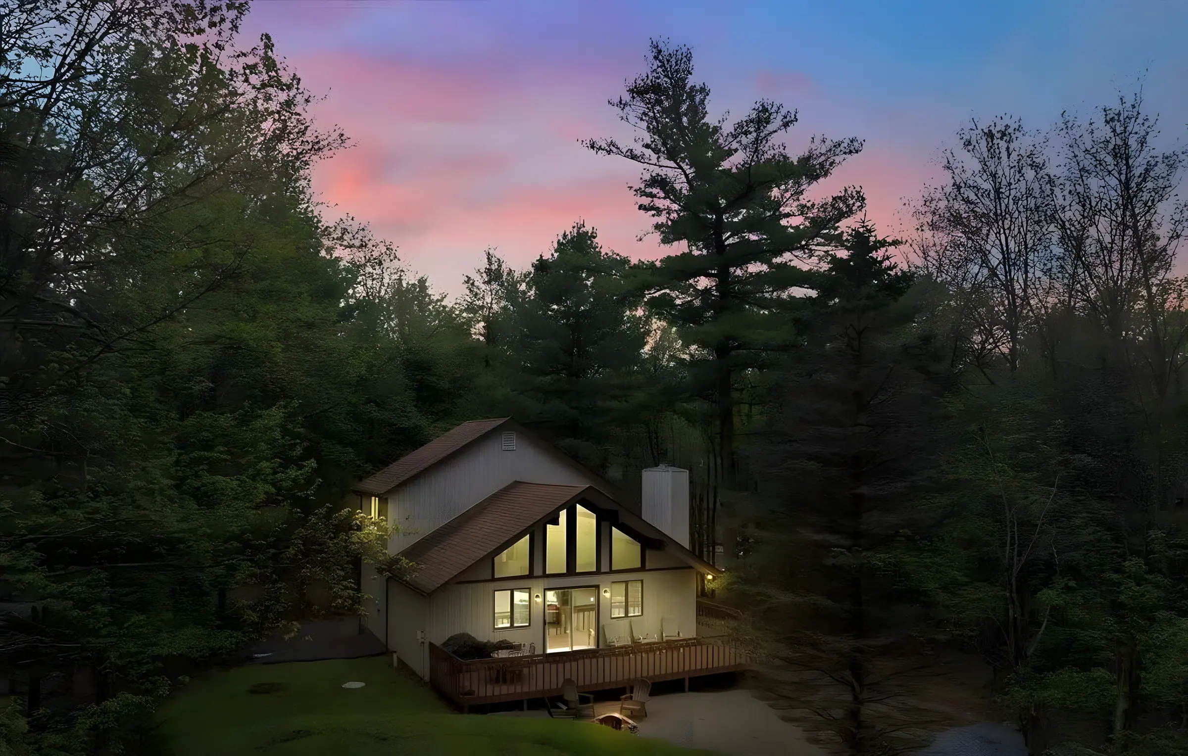 A-frame home glowing at dusk among tall pines at Get Lucky On Lupine, Lake Harmony, PA