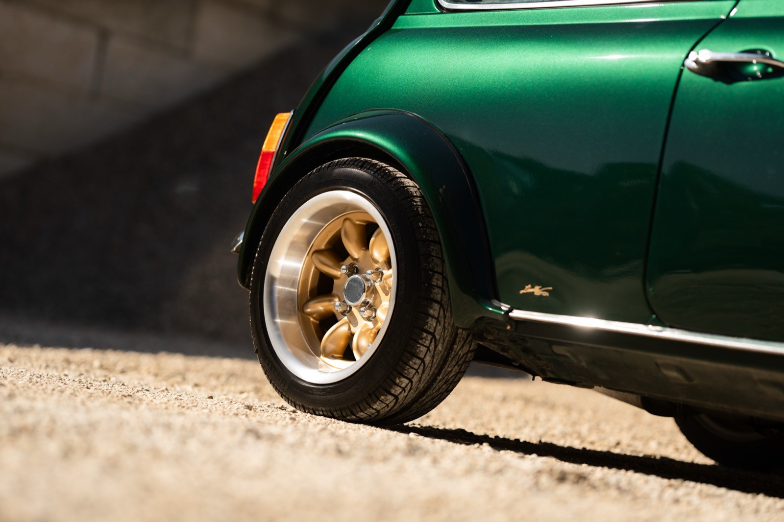 A small, green and black vehicle parked on a sandy surface, with a warm sunset lighting the scene.