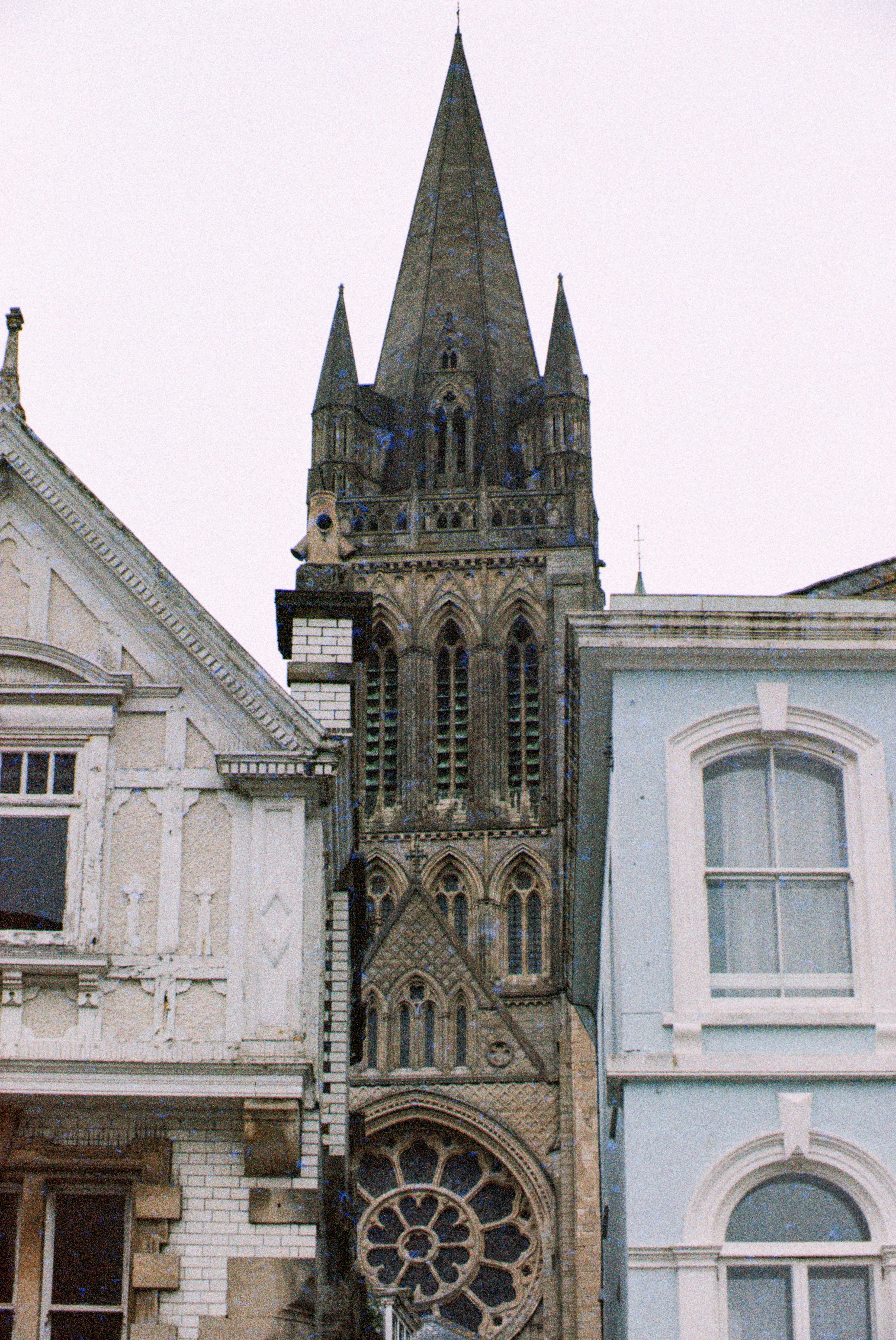 A church spire towers between two houses.