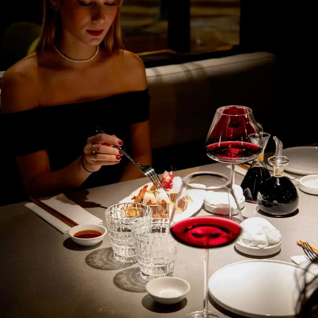 Une convive à une table dressée, un verre de vin rouge devant elle
