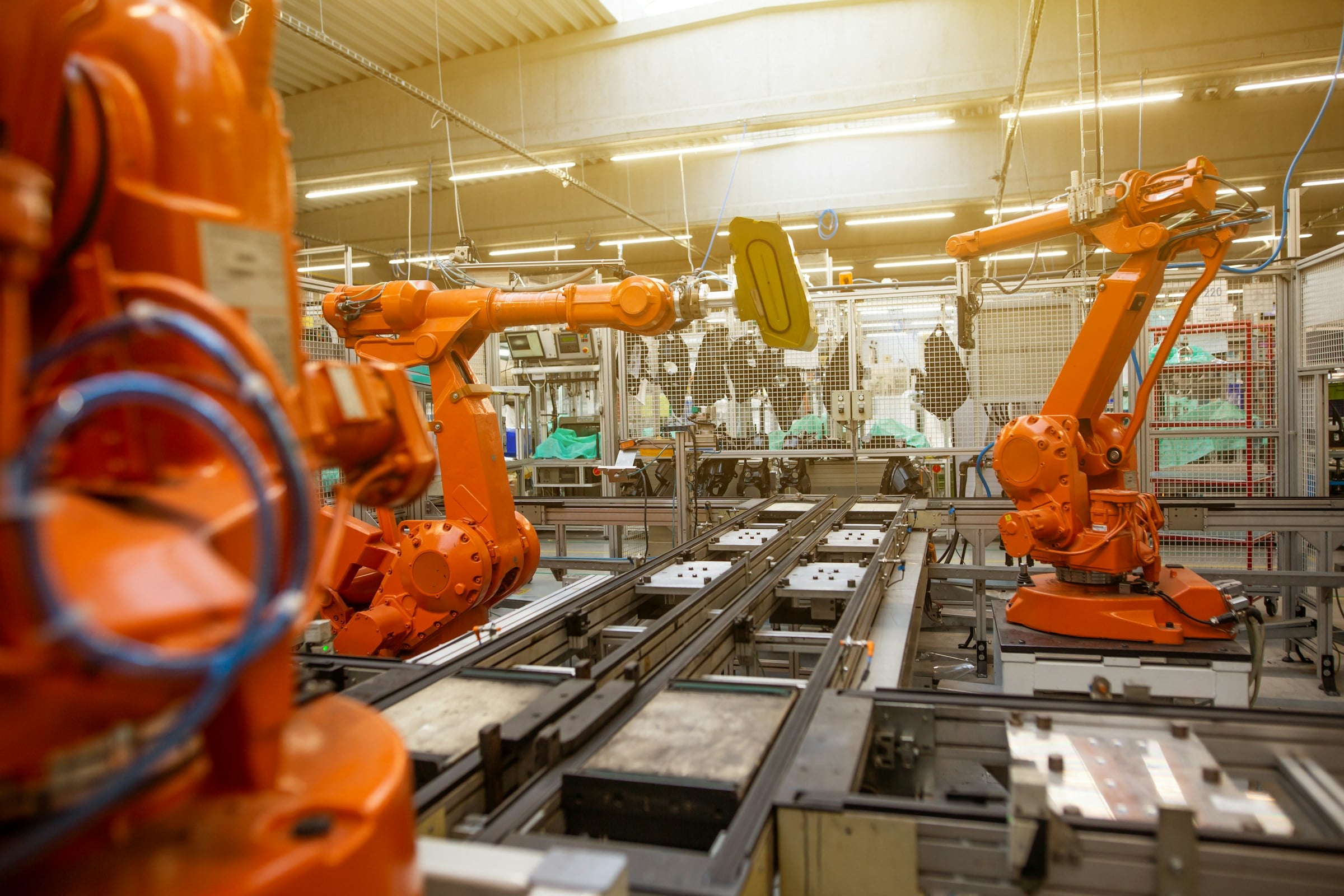Bras robotiques orange en fonctionnement dans une chaîne de production automatisée.
