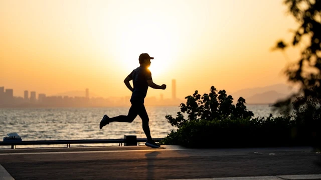 Runner silhouetted at sunset near the water