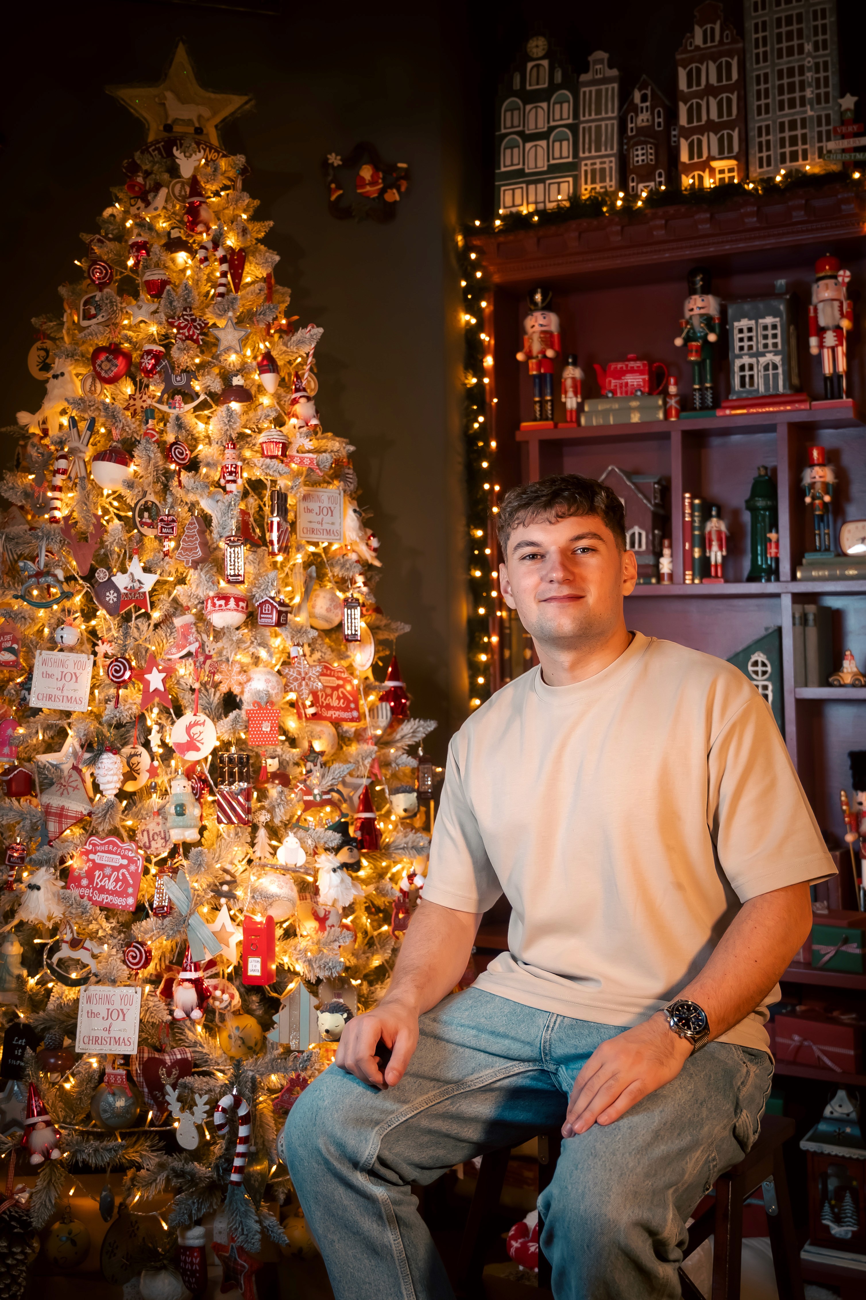 Portret de Crăciun cu tânăr într-un decor festiv cu brad împodobit și lumini calde, ședință foto de Crăciun București.