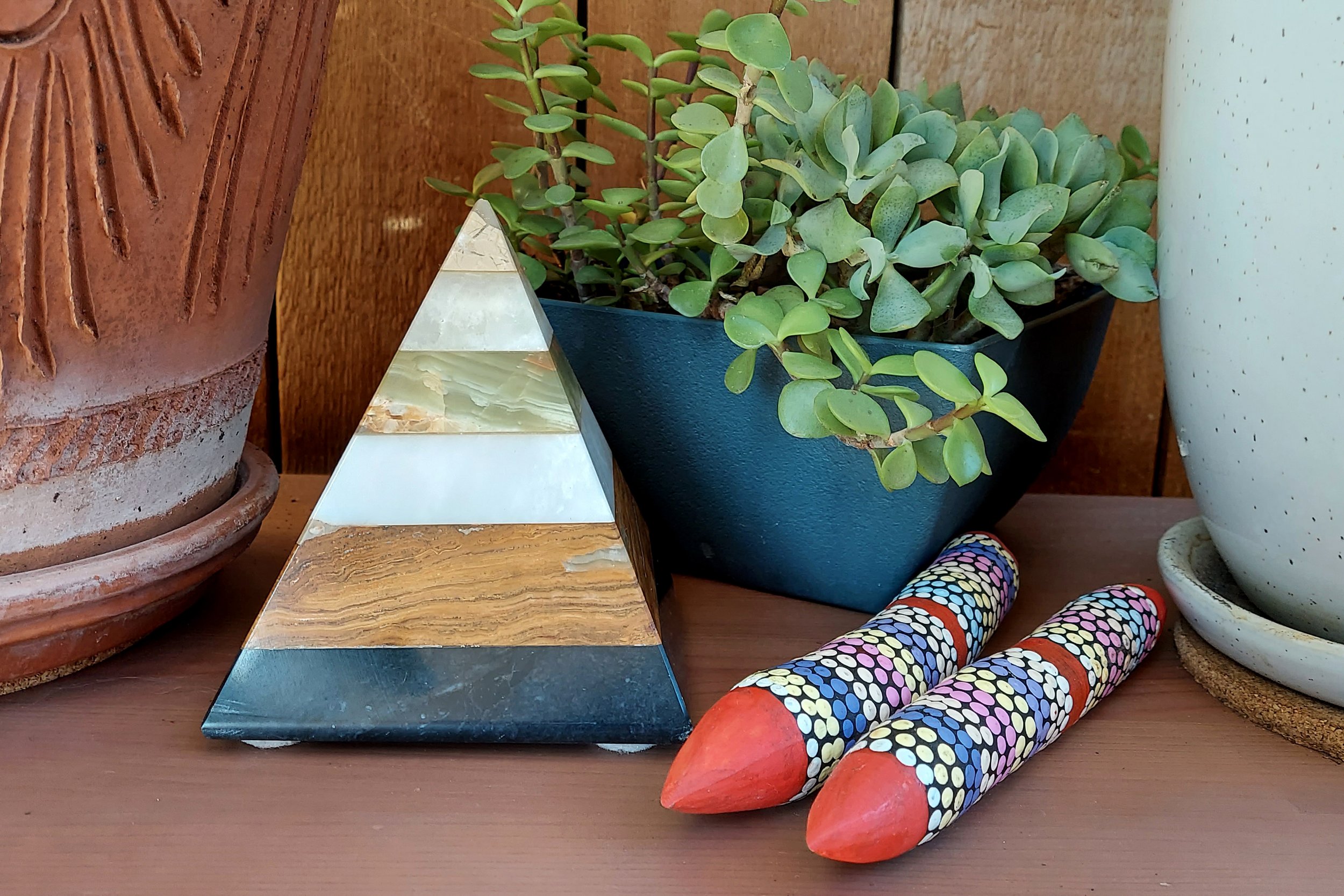 A triangular wooden object, a plant and ceramic pots arranged as a five element display