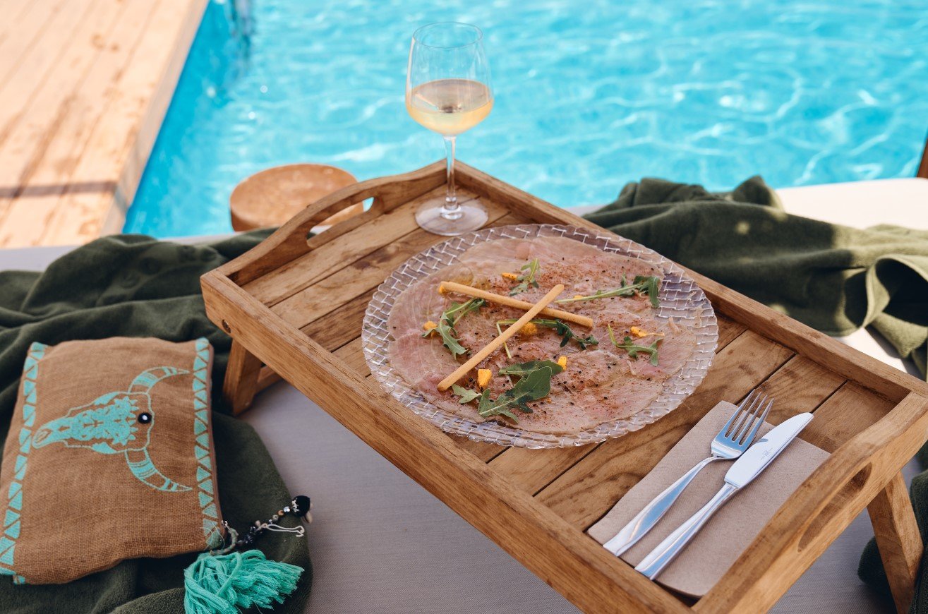 Rindercarpaccio mit Wein am Pool, serviert auf einem Holztablett.