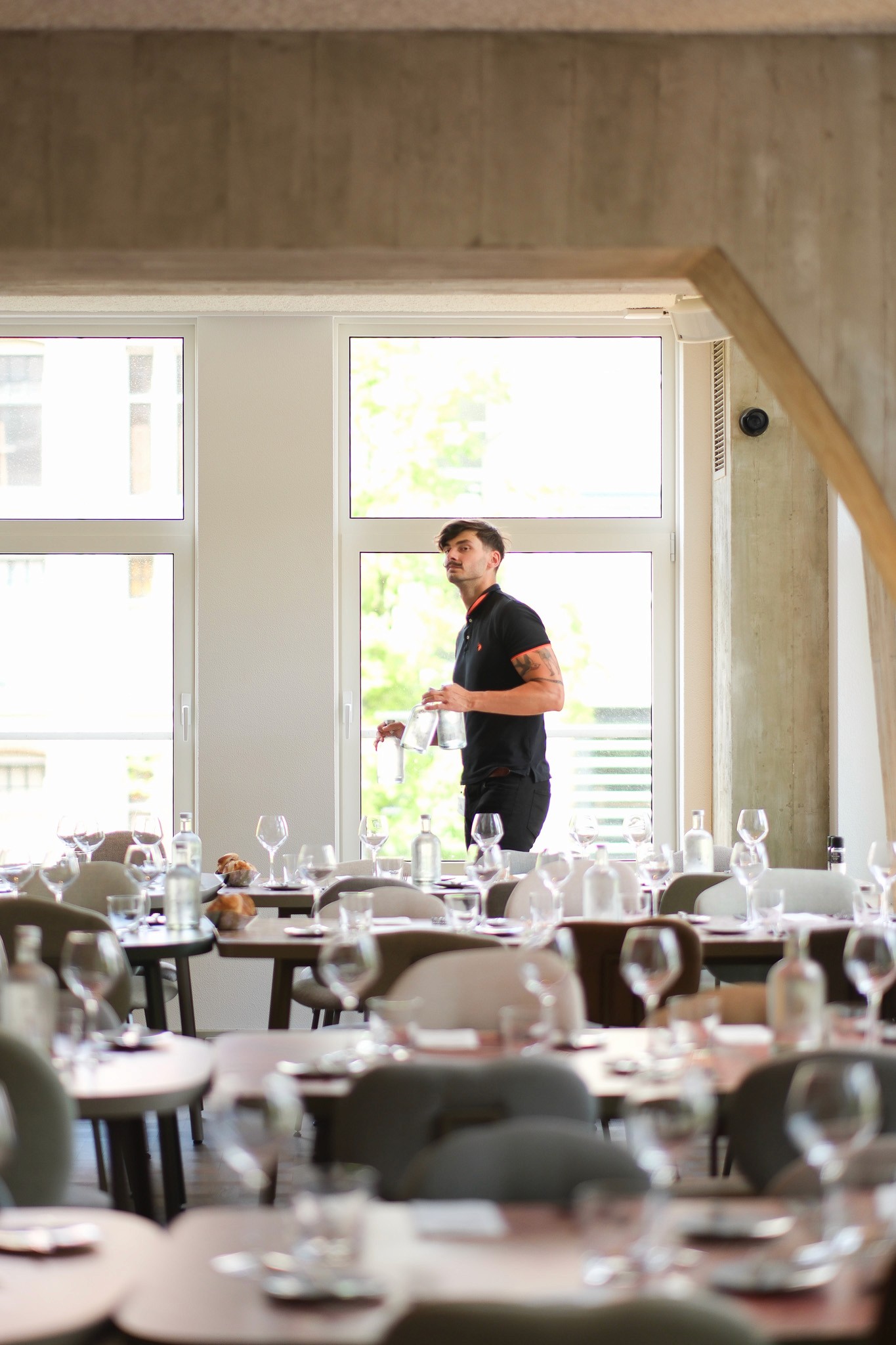 Staff setting the dining room for a private event at Capital Kitchen, with natural light streaming through large windows.