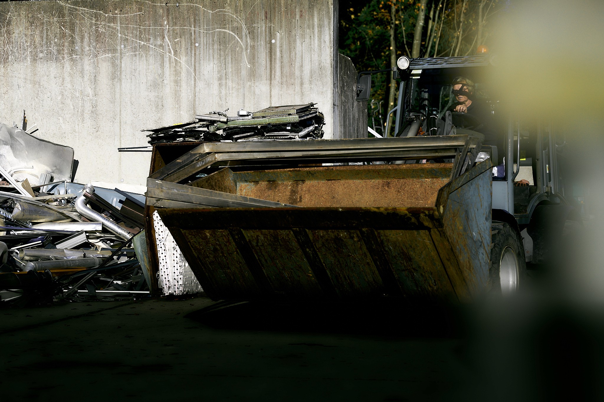 Ein Gabelstapler hebt einen Container voller Metallschrott auf einem Schrottplatz.