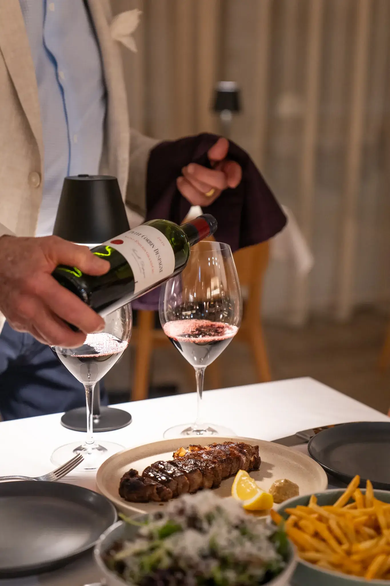 Waiter pouring wine beside a steak dinner at ANNATA Restaurant