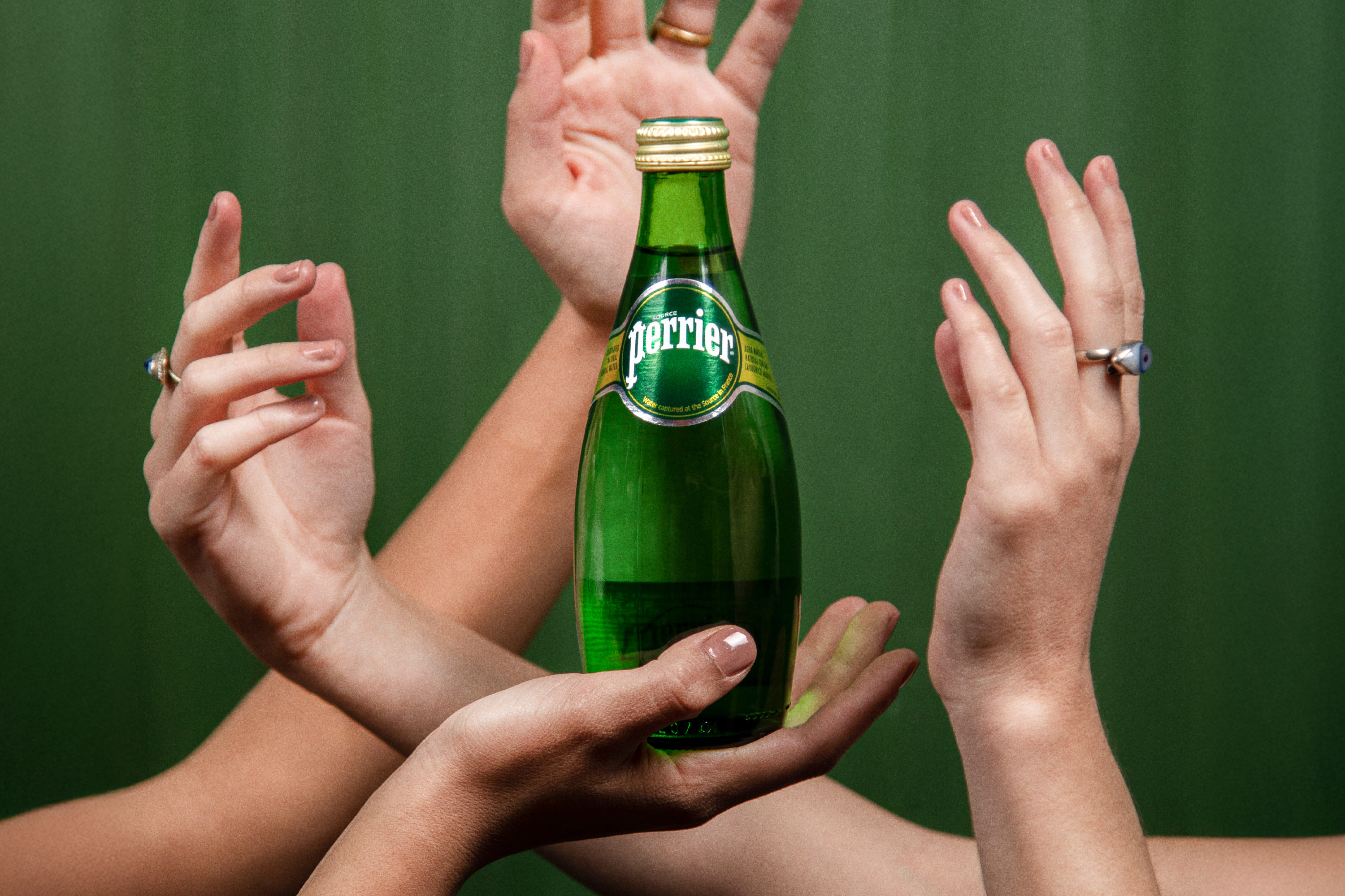 perrier bottle surrounded by hands