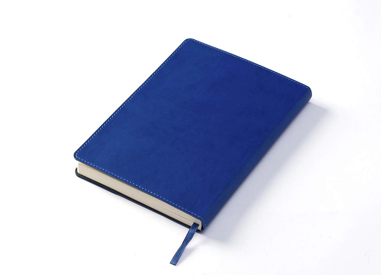 Angled back view of closed blue notebook with white stitching.