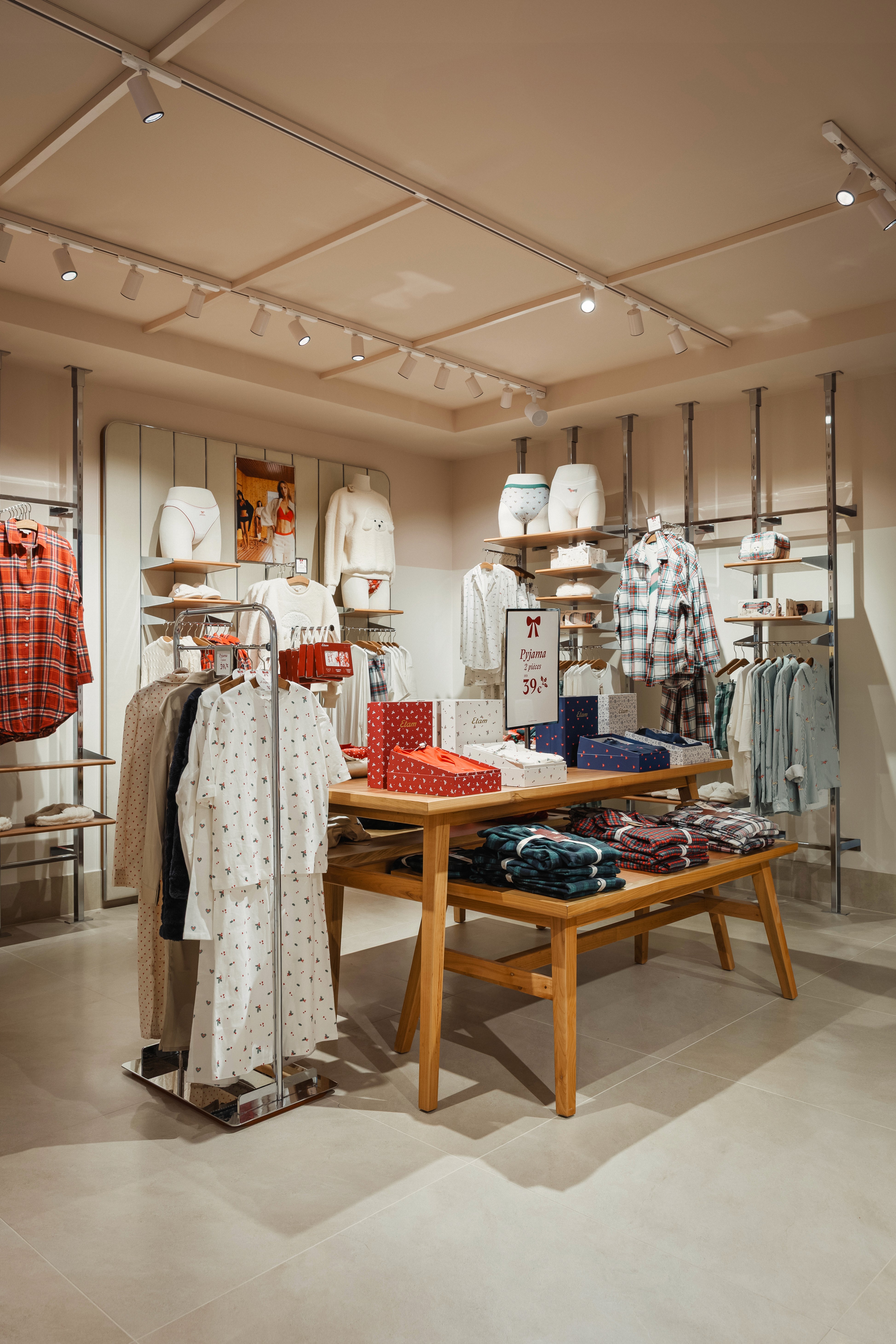 Table centrale avec coffrets cadeaux et vêtements pliés, cintres de pyjamas à motifs, ambiance chaleureuse