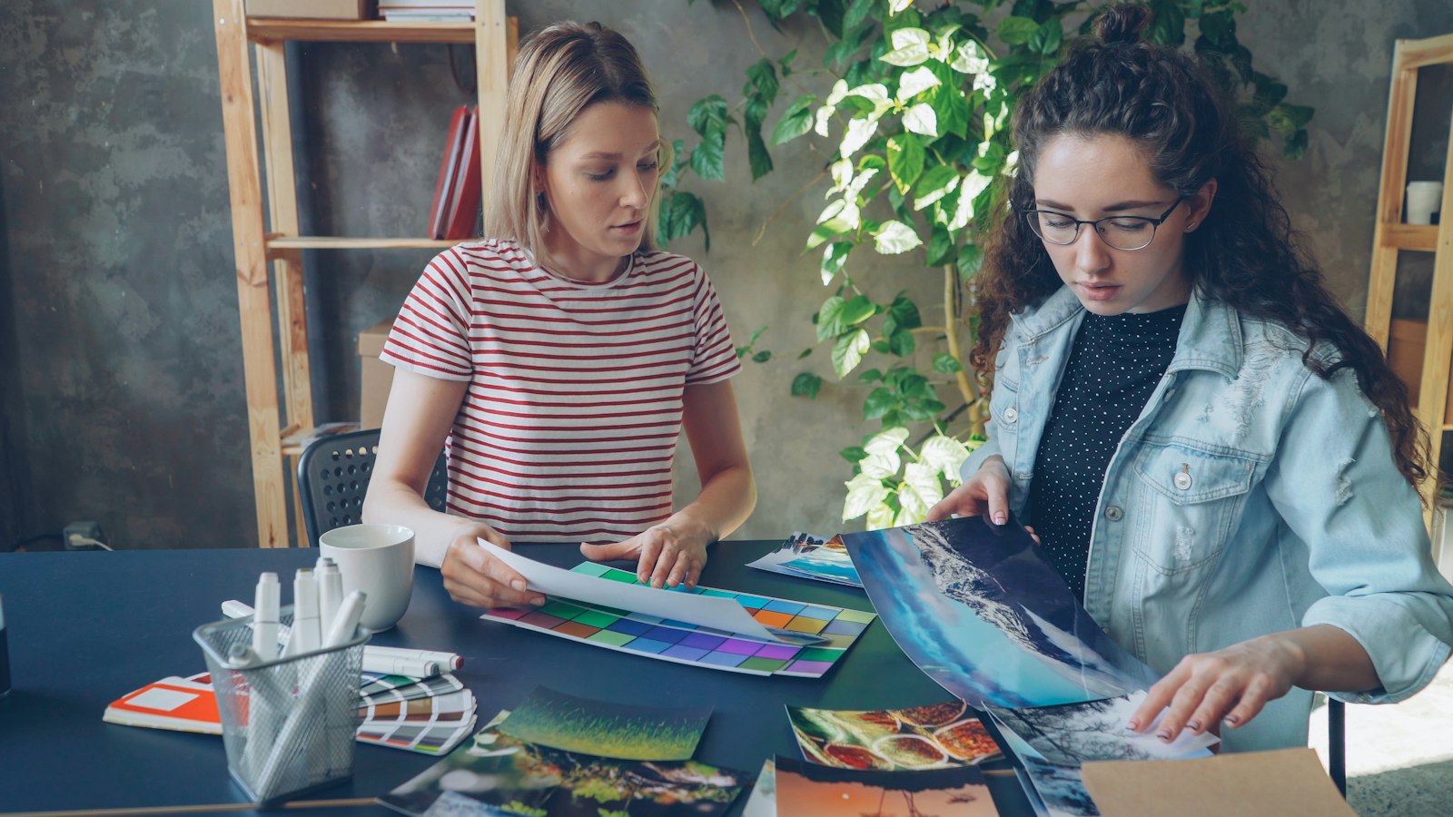 Two designers reviewing printed artwork together at the studio table