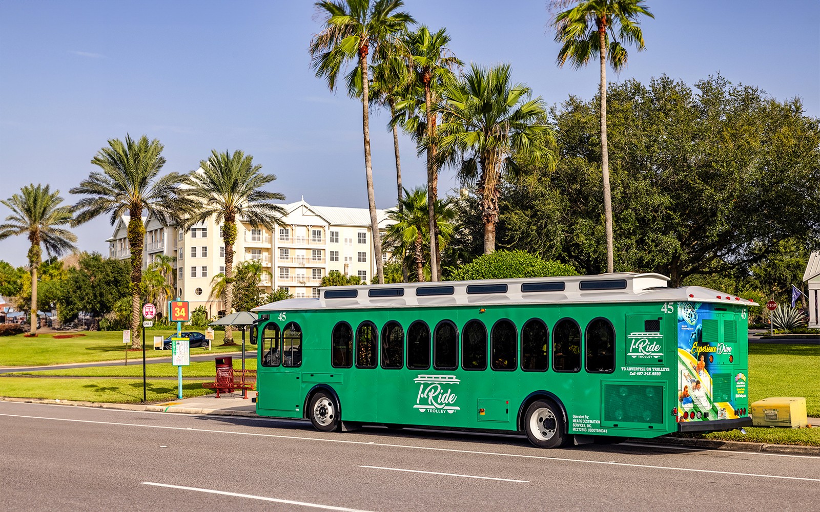 Orlando I-Ride trolley bus near palm trees and a hotel.