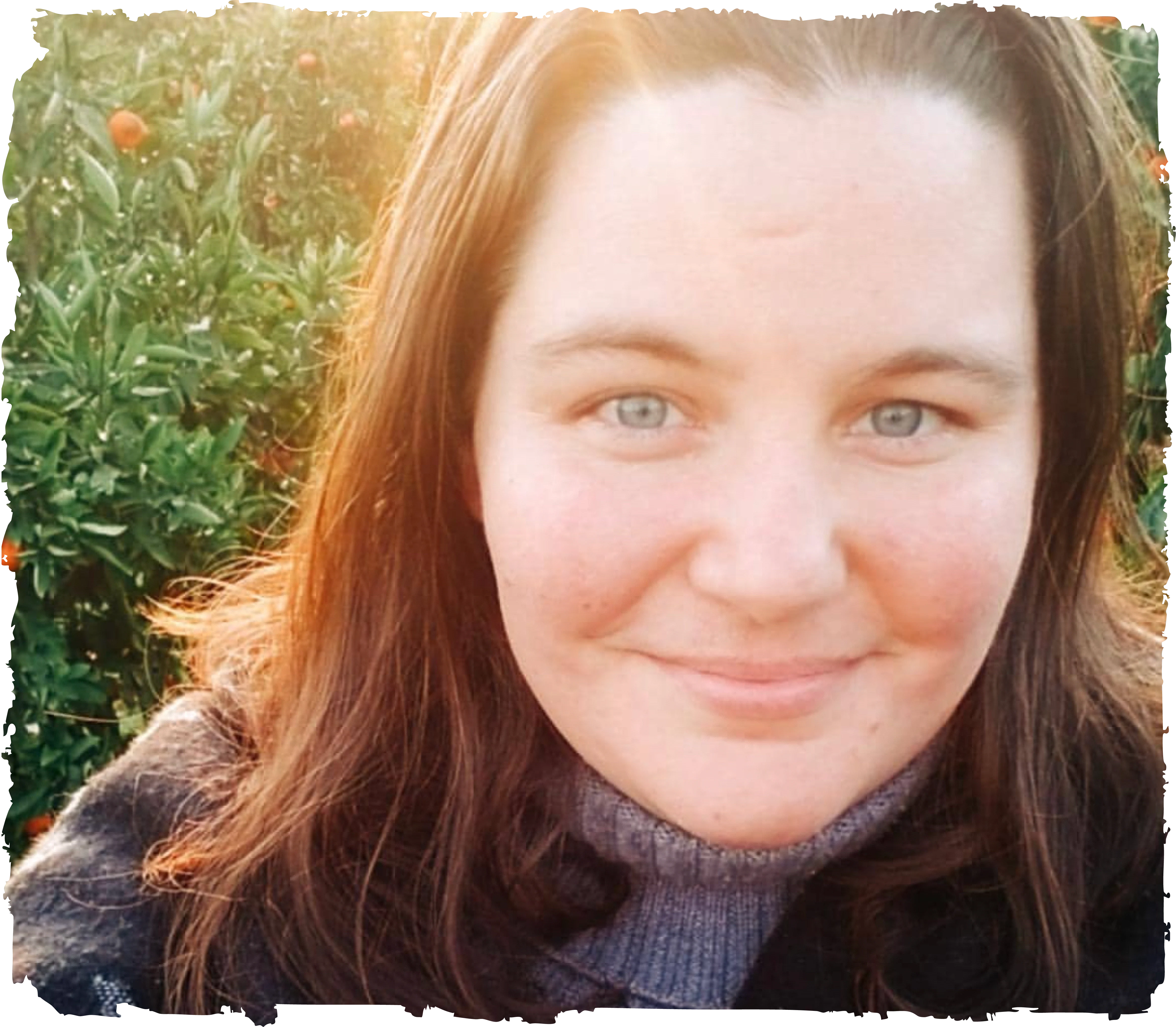 Jen Rego, brand identity designer, smiling in an orchard with warm backlight