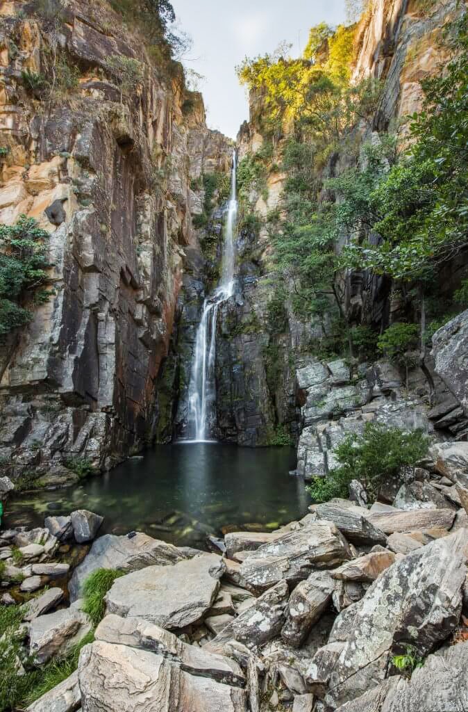 man standing near cliff looking at body of water during daytime