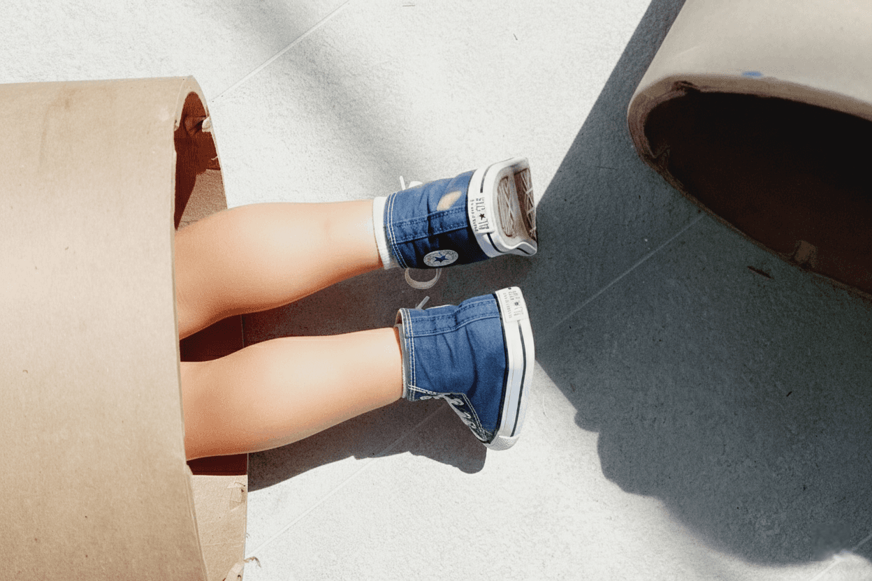 Pies de niño con zapatillas azules dentro de una caja, simbolizando la exploración lúdica y el descubrimiento