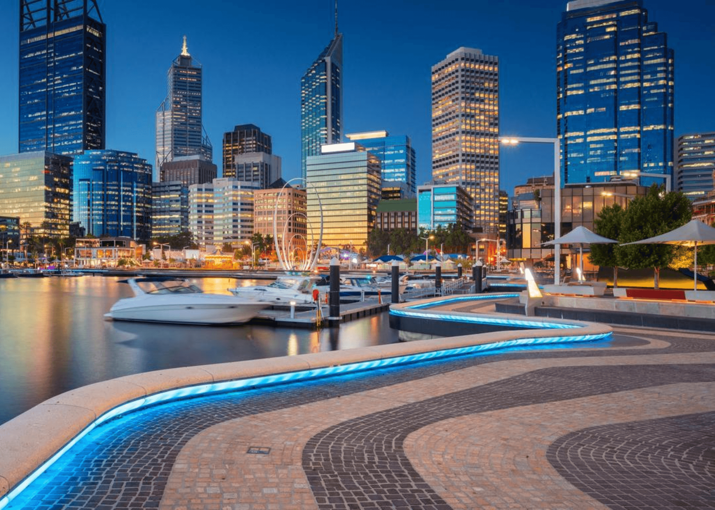 City skyline and waterfront at dusk with boats.