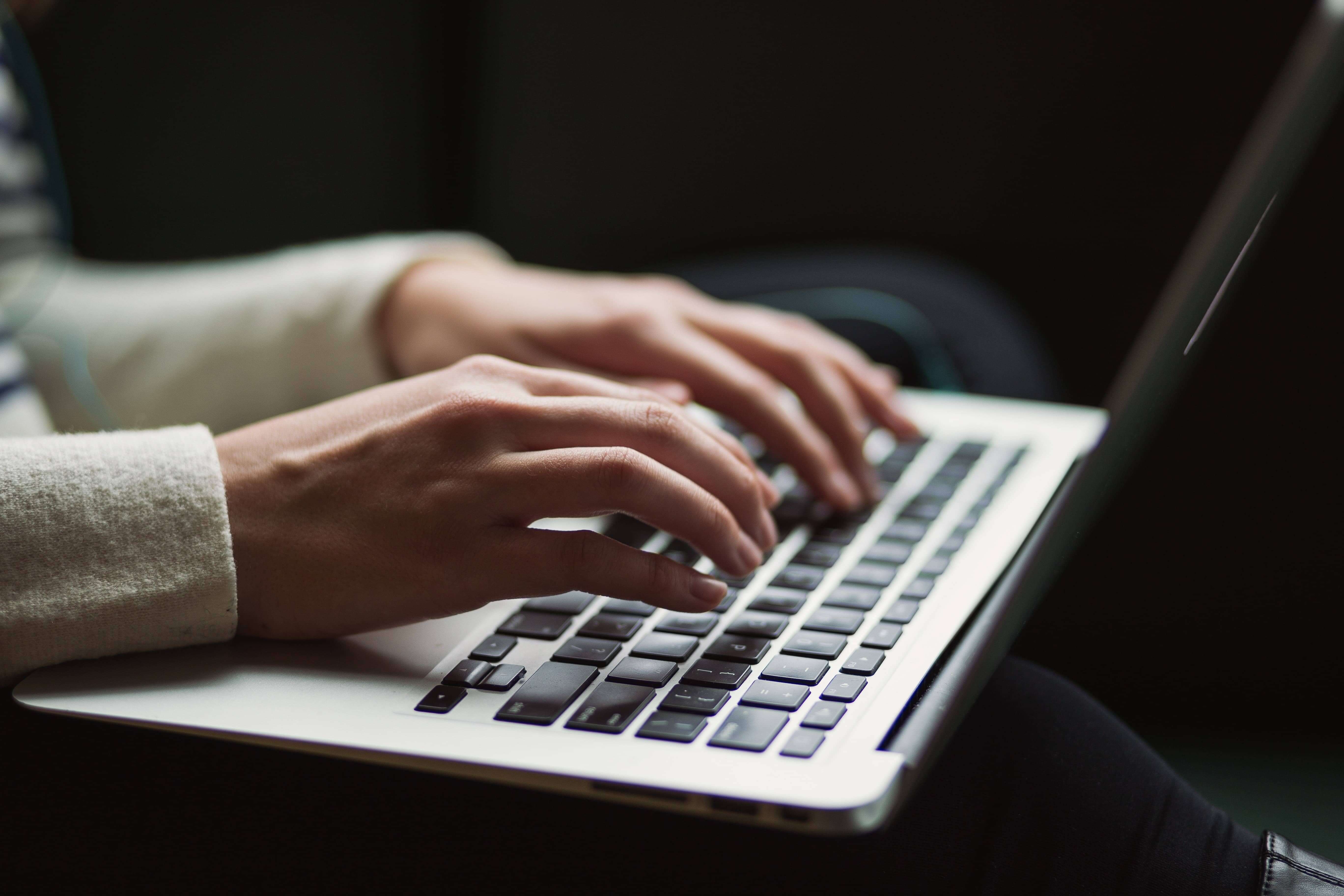 A woman is typing on a laptop | “Let us march!” Creating content that captivates & converts | Khula Design Studio