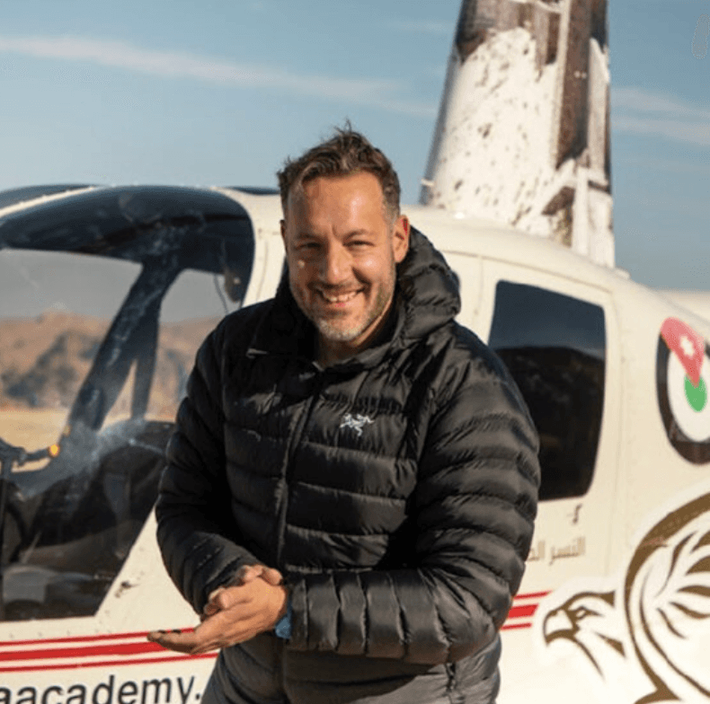 Regenesis guest standing beside a helicopter in a desert landscape