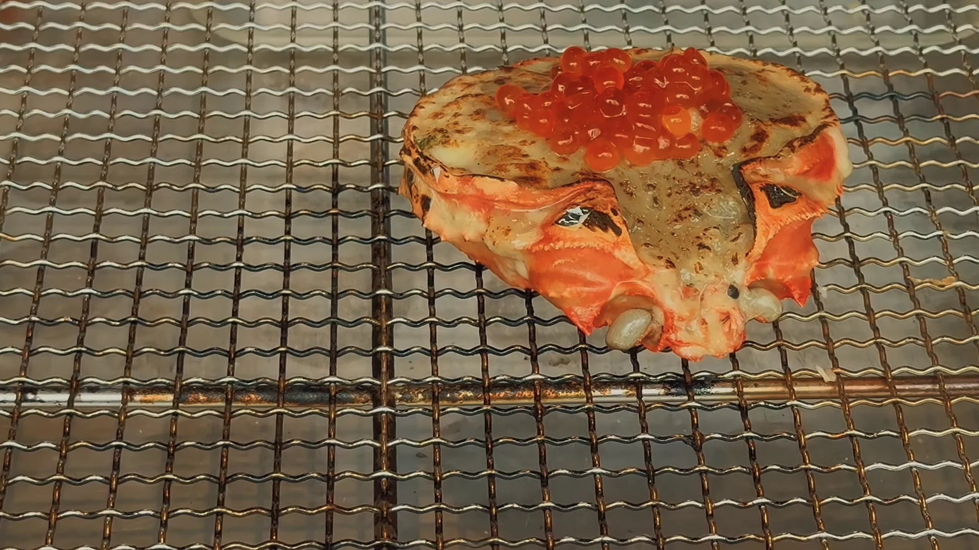 Crab grilling in its own shell over charcoal at a Kinosaki inn.