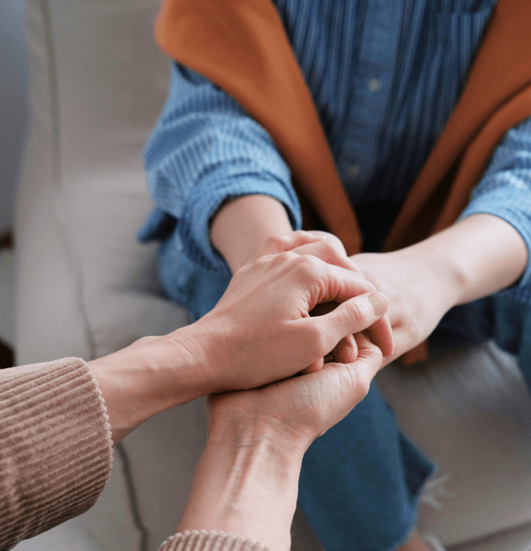 Close-up of two people holding hands in a comforting gesture, symbolizing mental health support during the war in Ukraine.